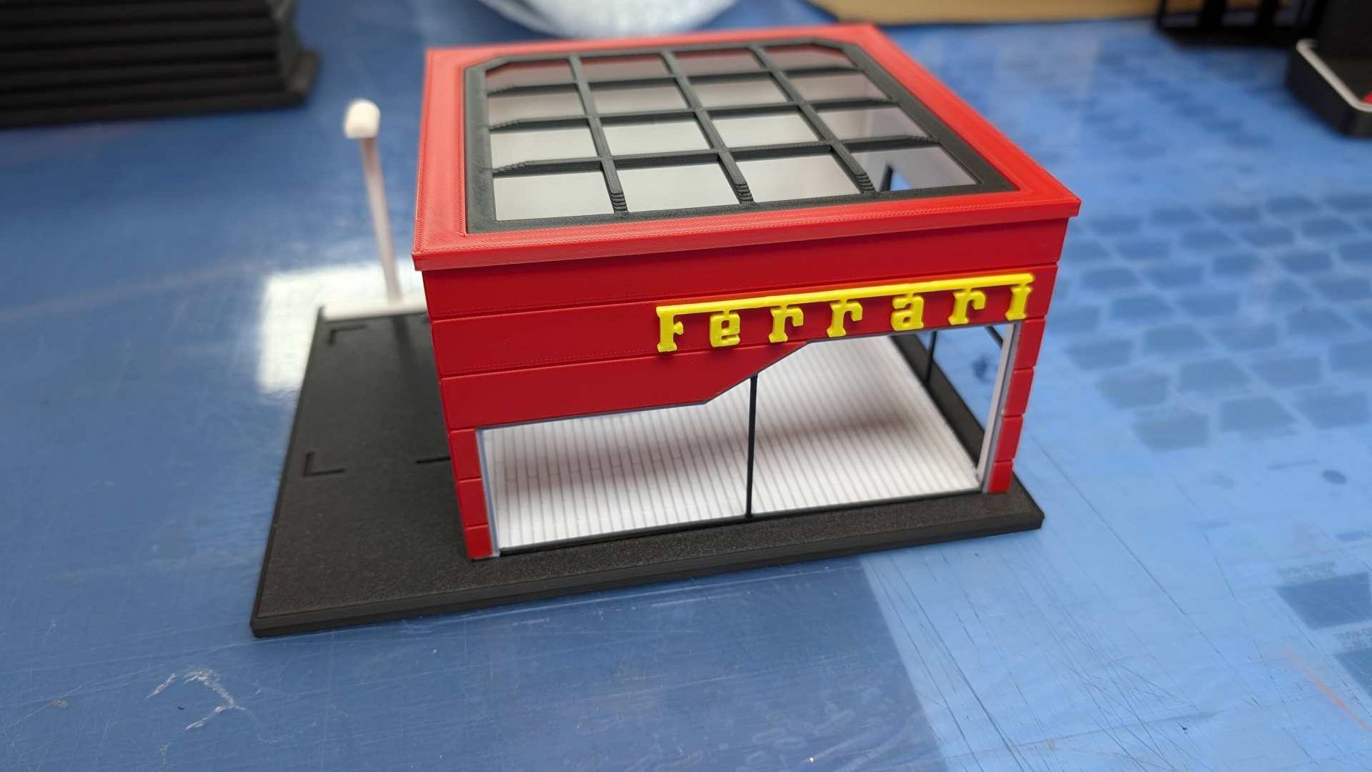 Modelo miniatura estrutura vermelha com letras amarelas Ferrari no topo