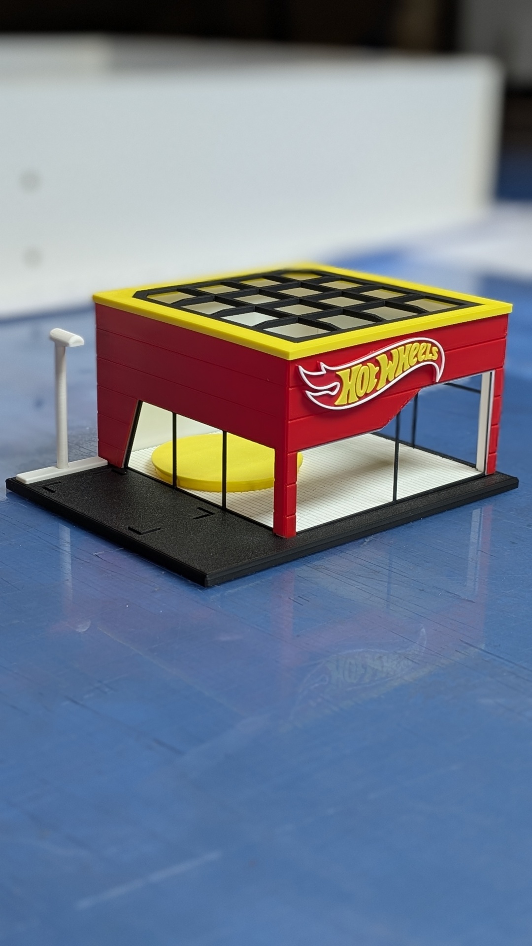 Miniatura de loja Hot Wheels em plástico vermelho e amarelo com base preta