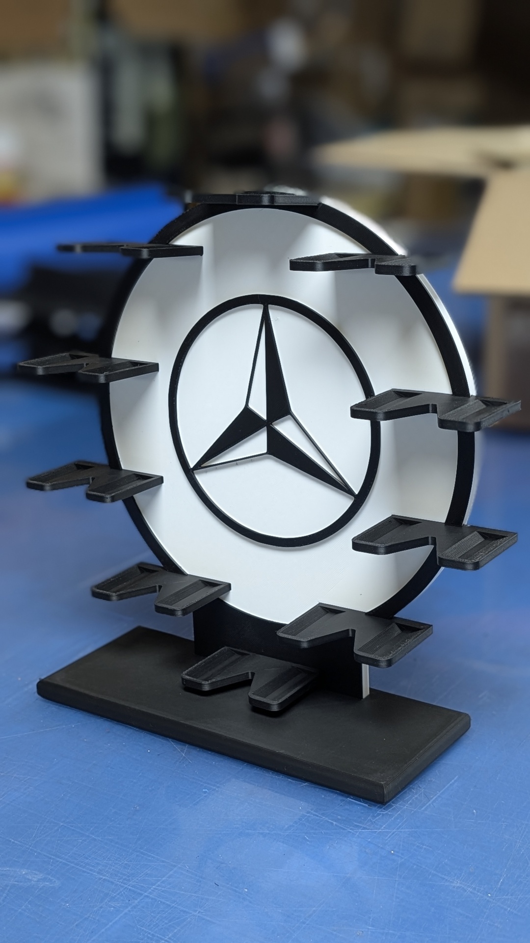 Suporte de exposição circular preto e branco com símbolo da Mercedes-Benz e plataformas pretas