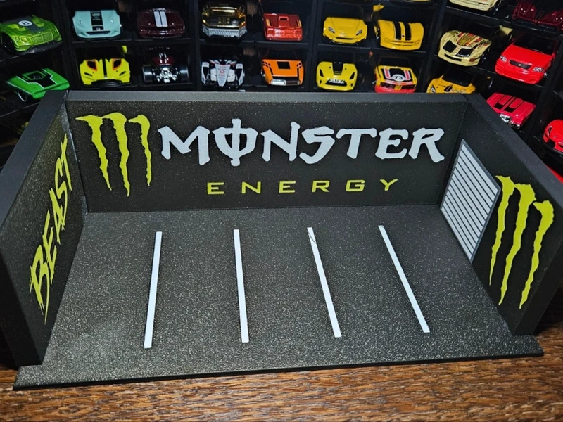 Base cinza texturizada MONSTER ENERGY para carros de brinquedo com carros coloridos no fundo