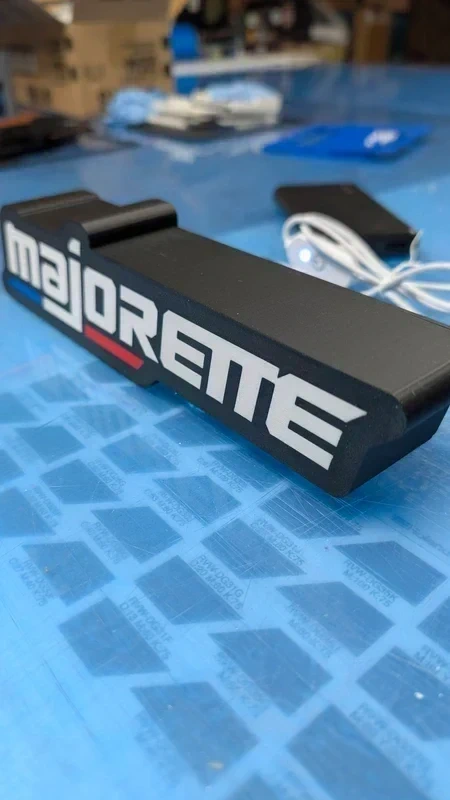 Objeto preto com texto MAJORETTE em branco e vermelho sobre superfície azul com padrões