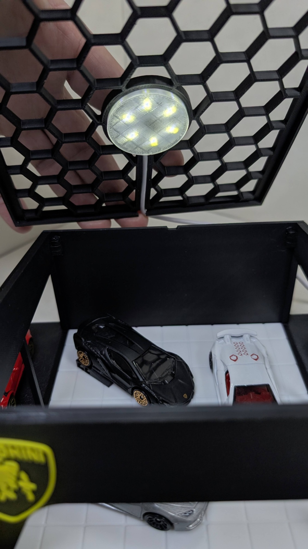 Miniaturas de carros dentro de caixa preta com tampa de rede e luz LED