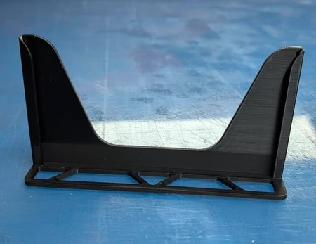 Suporte preto de plástico com base retangular e duas extremidades verticais altas sobre superfície azul.