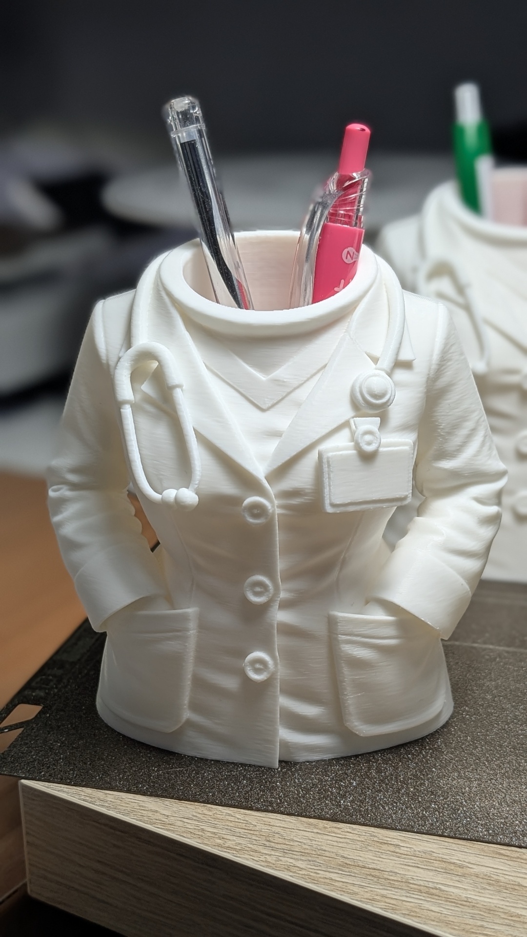 Suporte para canetas em forma de bata médica branca com detalhes de estetoscópio