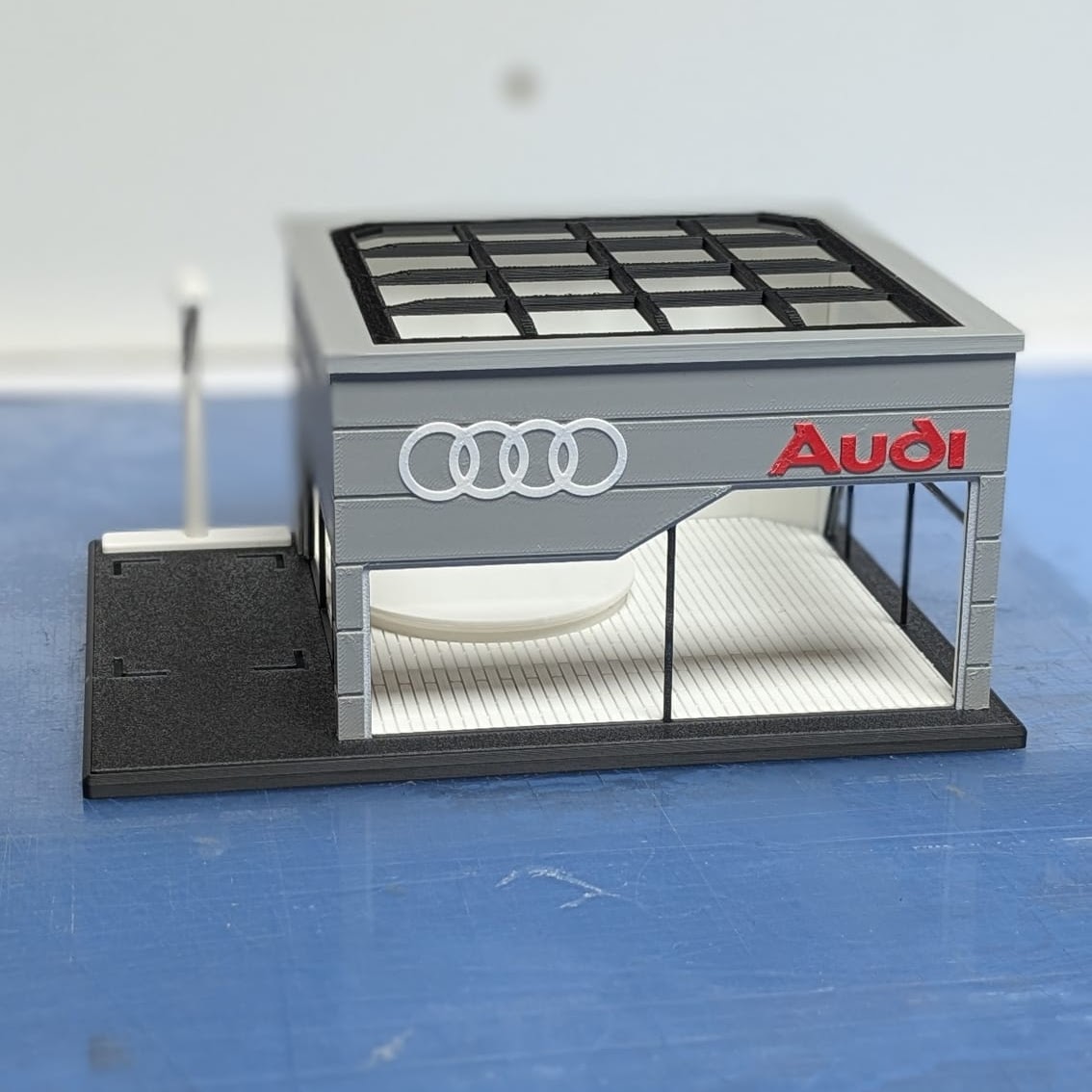 Maquete de edifício cinzento com logotipo Audi e teto aberto