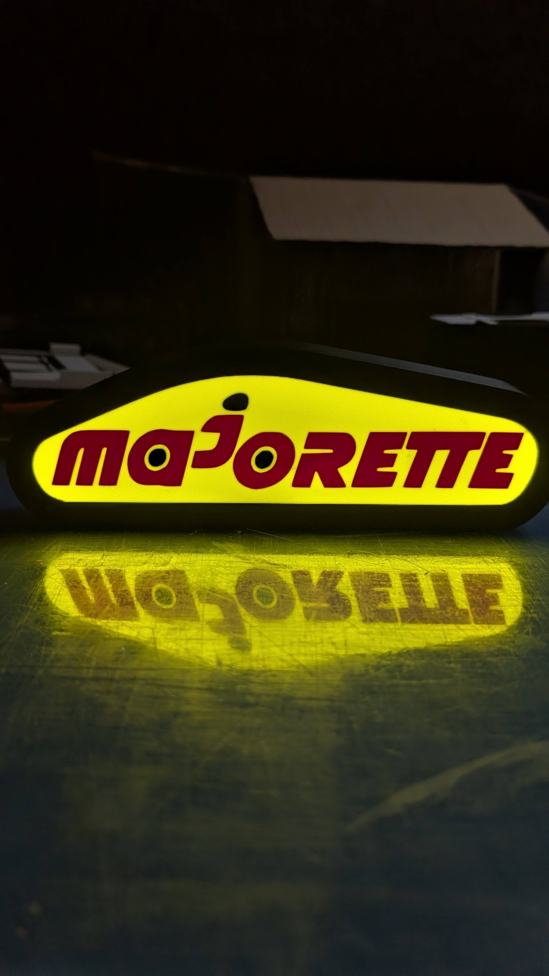 Sinal luminoso amarelo com texto MAJORETTE em vermelho