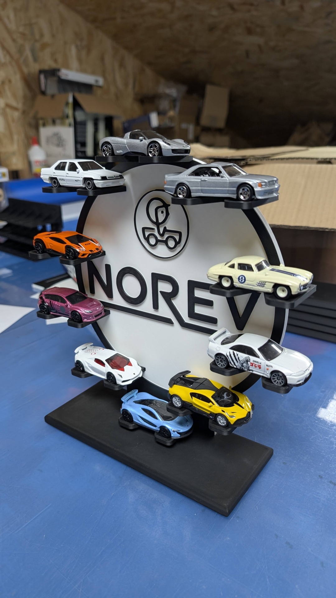 Miniaturas de carros desportivos coloridos expostas em suporte com logo NOREV