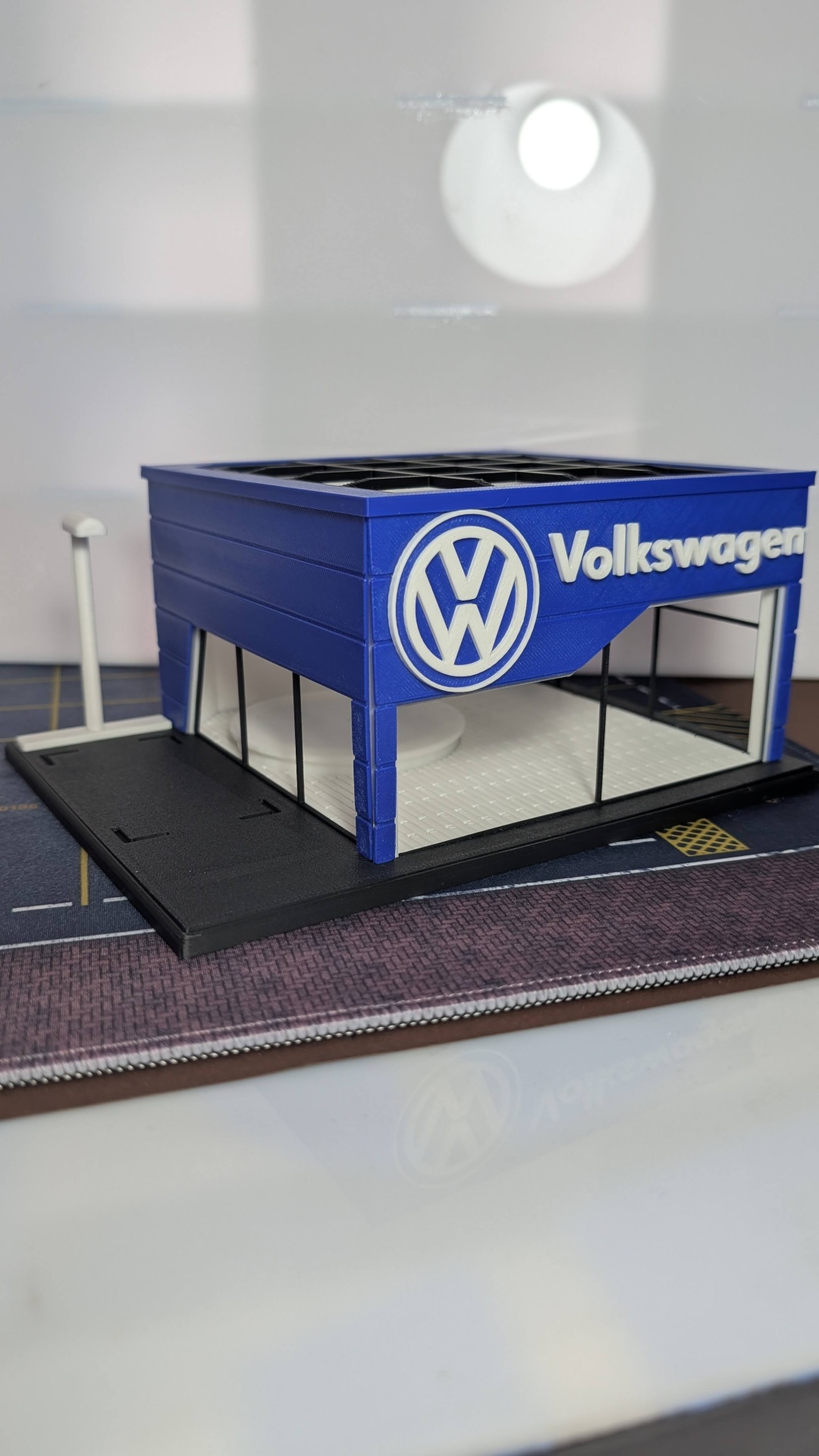 Miniatura de concessionária Volkswagen azul com logótipo e texto branco