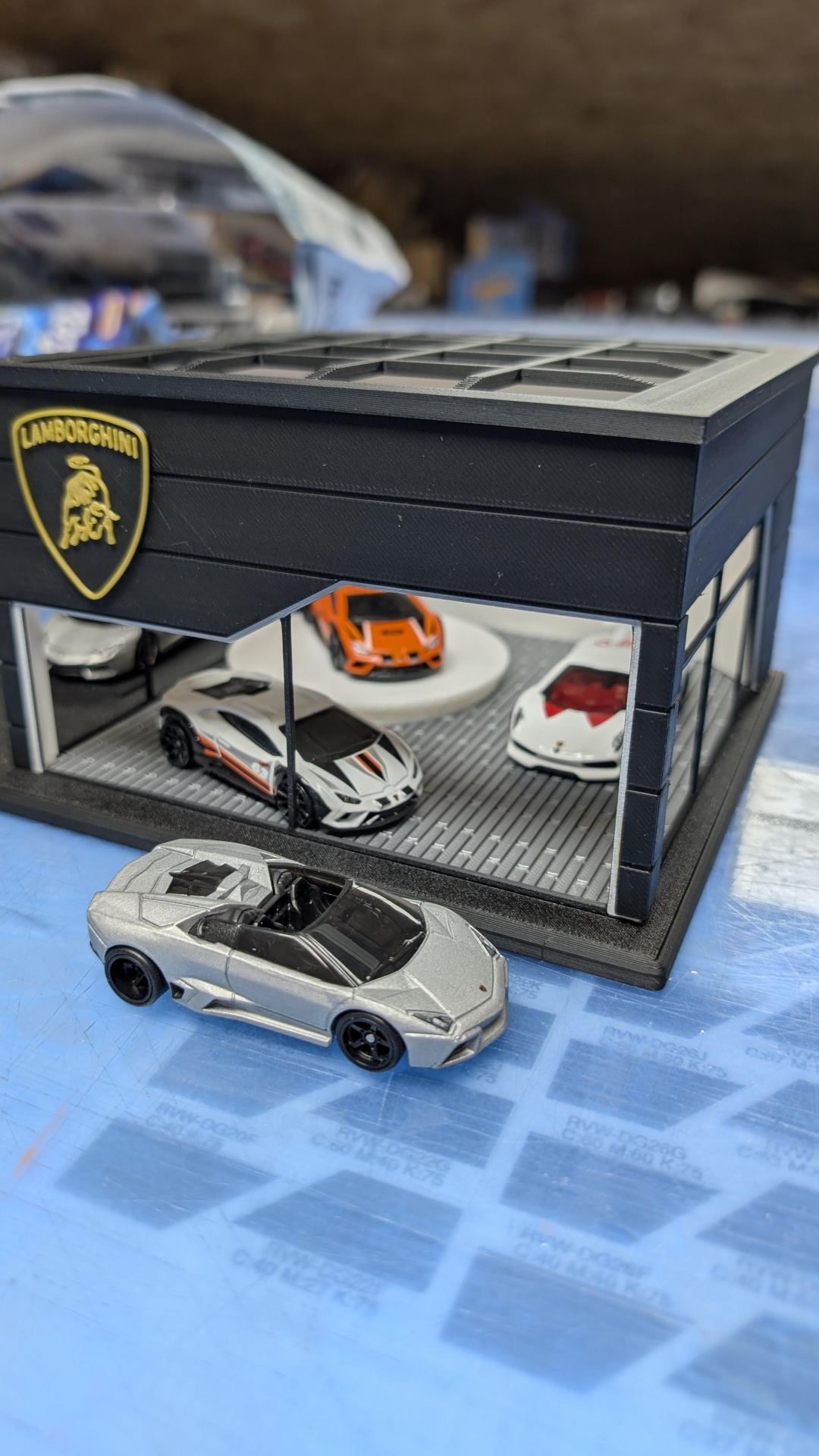 Miniaturas de carros Lamborghini e estande preto com logótipo dourado