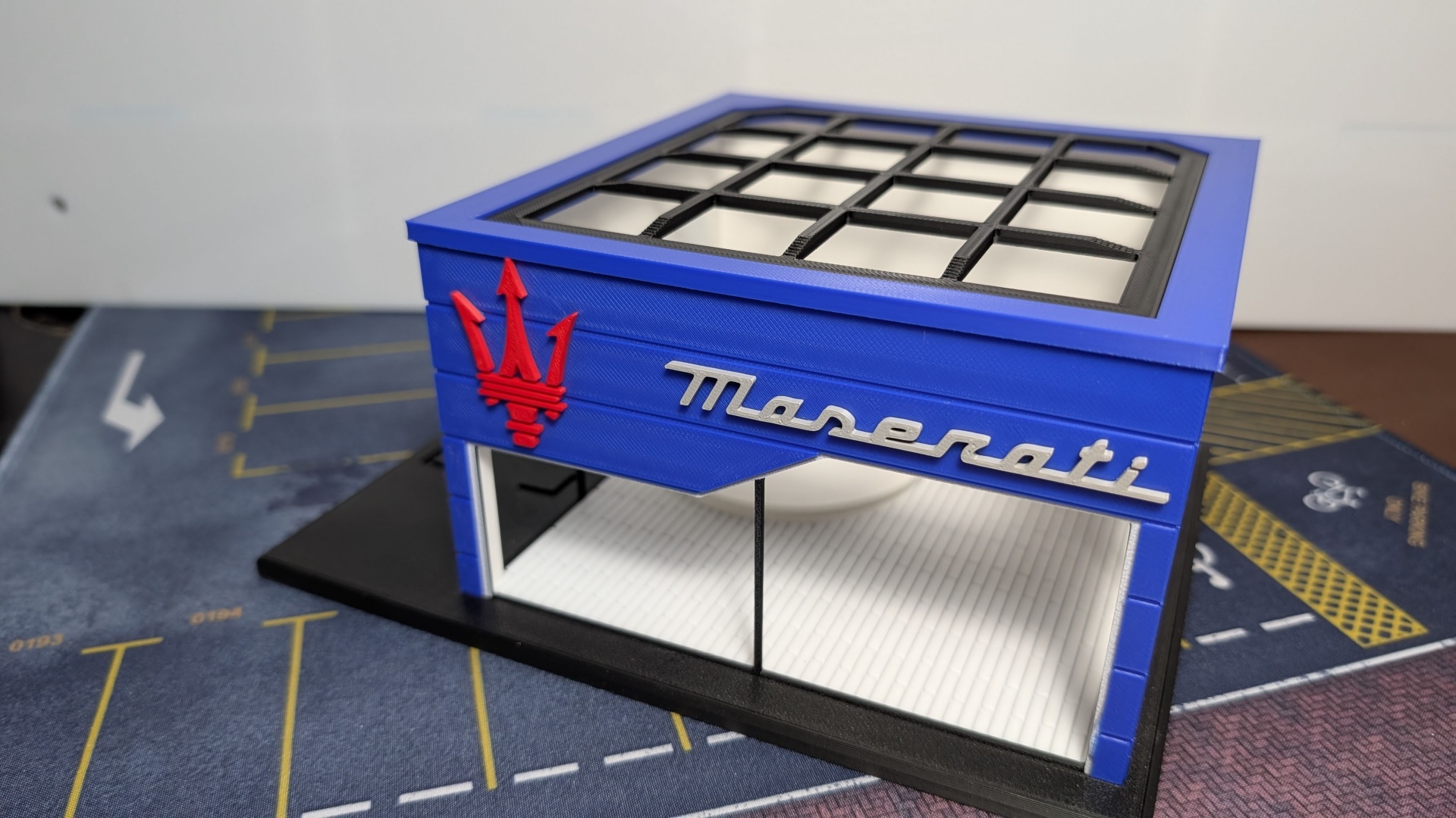 Miniatura loja Maserati azul com logotipo vermelho e texto prateado