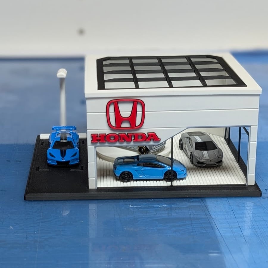 Modelo miniatura de loja Honda com carros de brinquedo azuis e cinza.