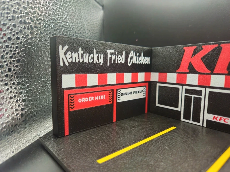 Miniatura da fachada do restaurante KFC em material rígido com textos e faixas no chão