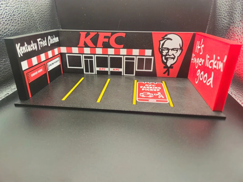 Miniatura de restaurante KFC com estacionamento e textos promocionais.