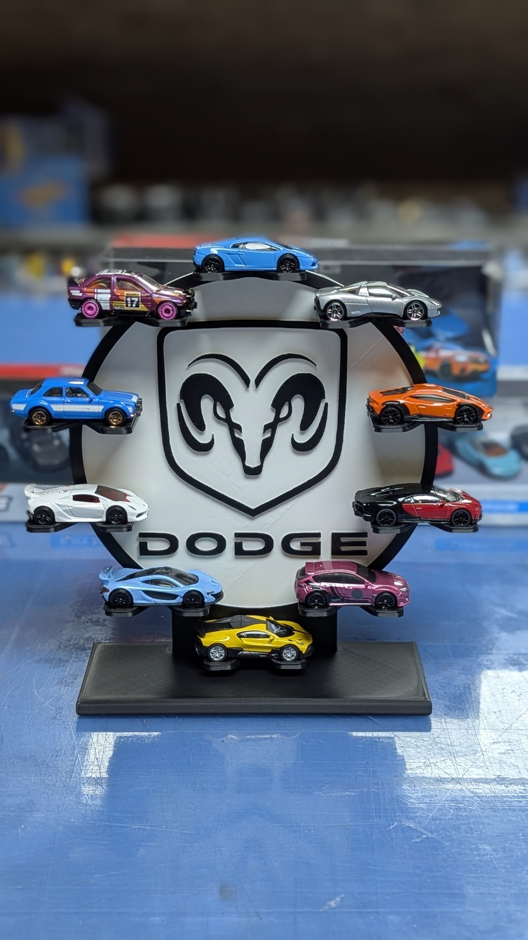 Conjunto de carros miniatura em várias cores expostos num suporte com o logótipo Dodge.