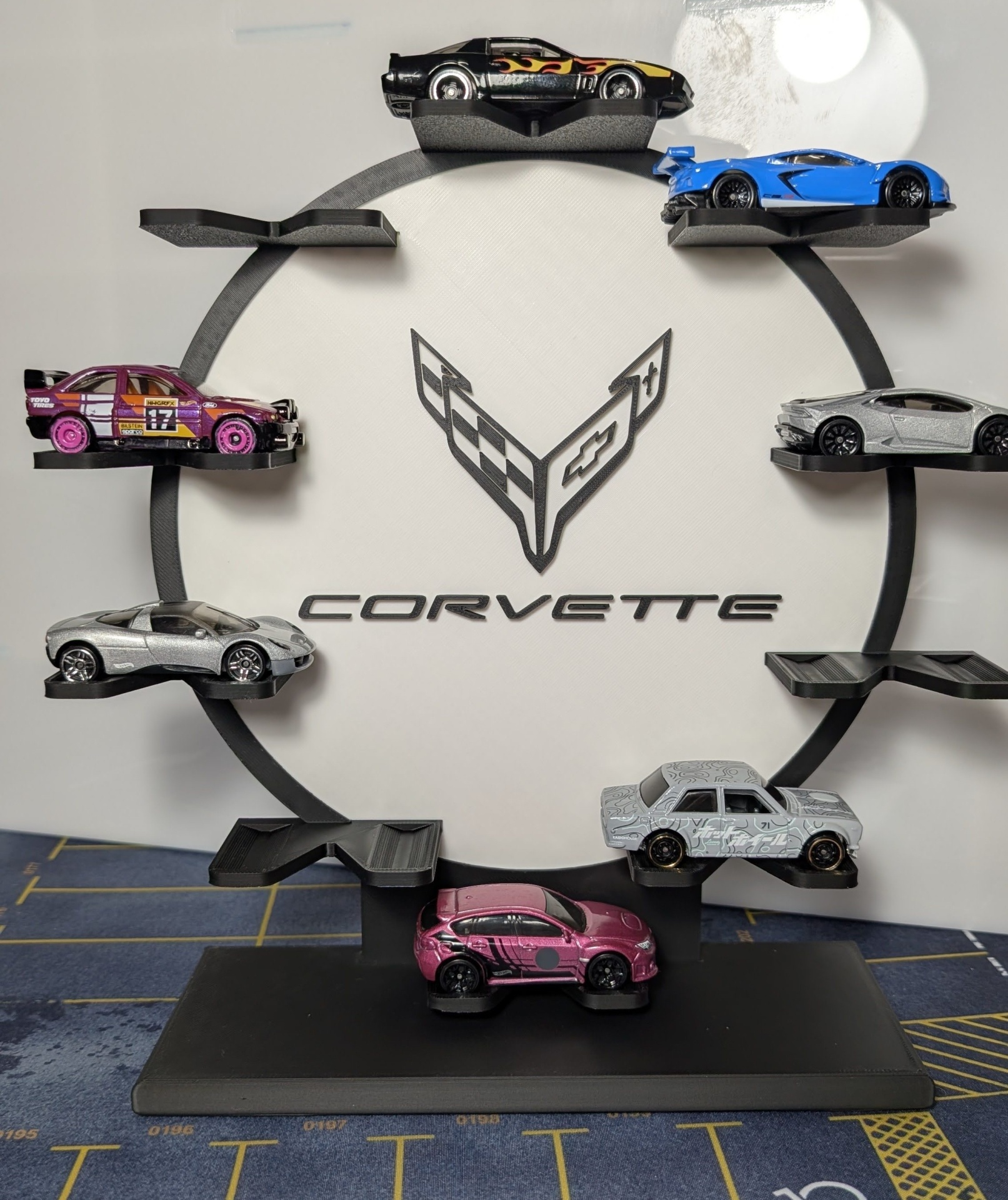 Porta-coleção preto com miniaturas de carros e logotipo Corvette em fundo branco