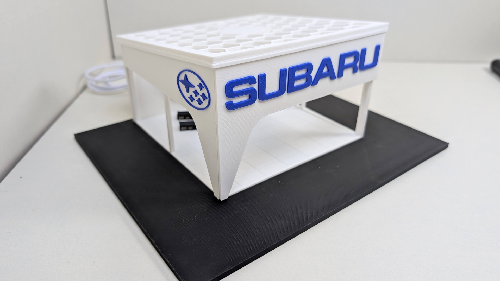 Miniatura branca com texto SUBARU em azul sobre base preta