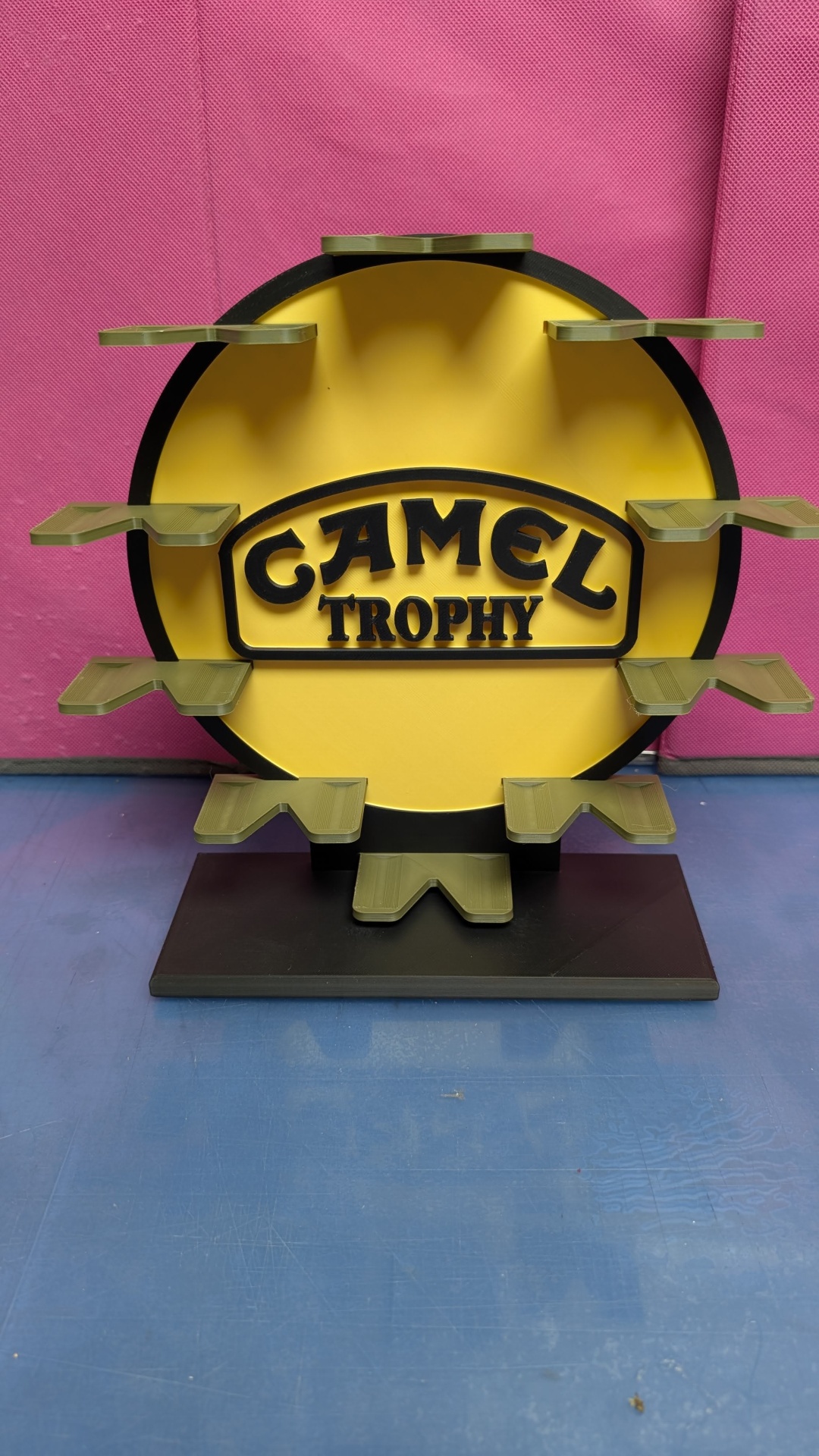 Suporte amarelo e preto com texto CAMEL TROPHY e várias plataformas verdes