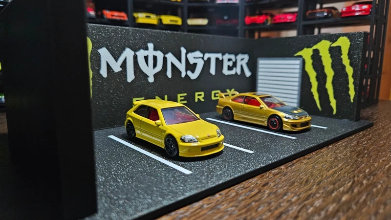 Miniaturas de carros amarelos em parque de estacionamento em miniatura com decoração MONSTER ENERGY