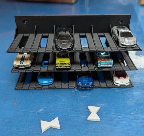 Porta-carros preto com miniaturas coloridas, em três níveis sobre superfície azul