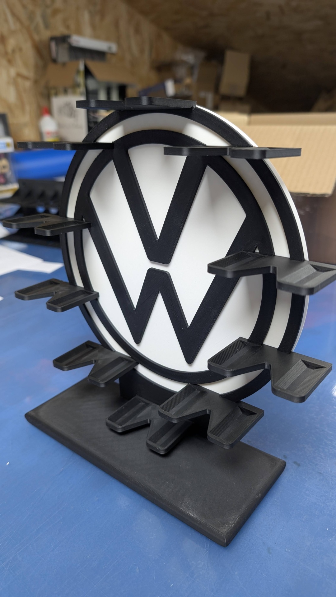 Suporte preto e branco com letras VW e prateleiras retangulares.