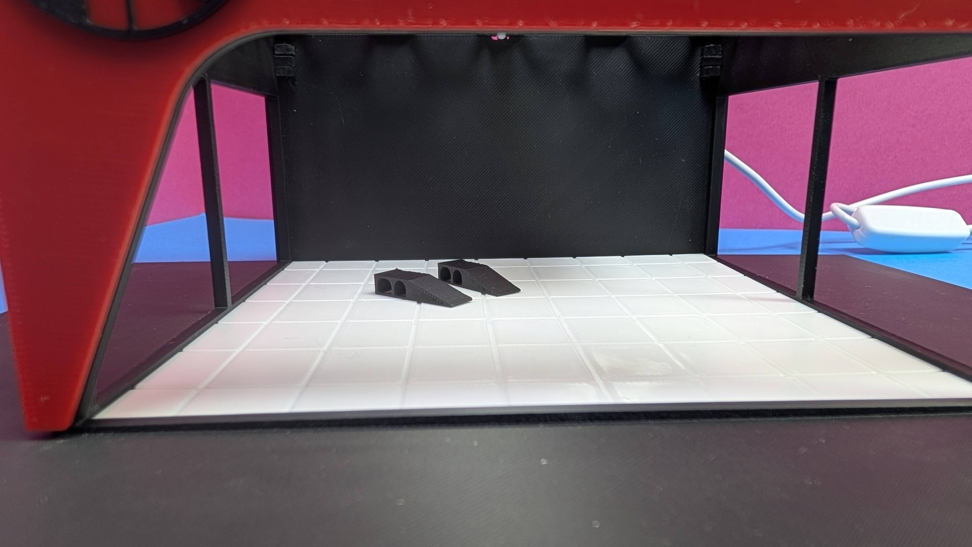 Mini palco caixa vermelha com chão branco e dois objetos pretos