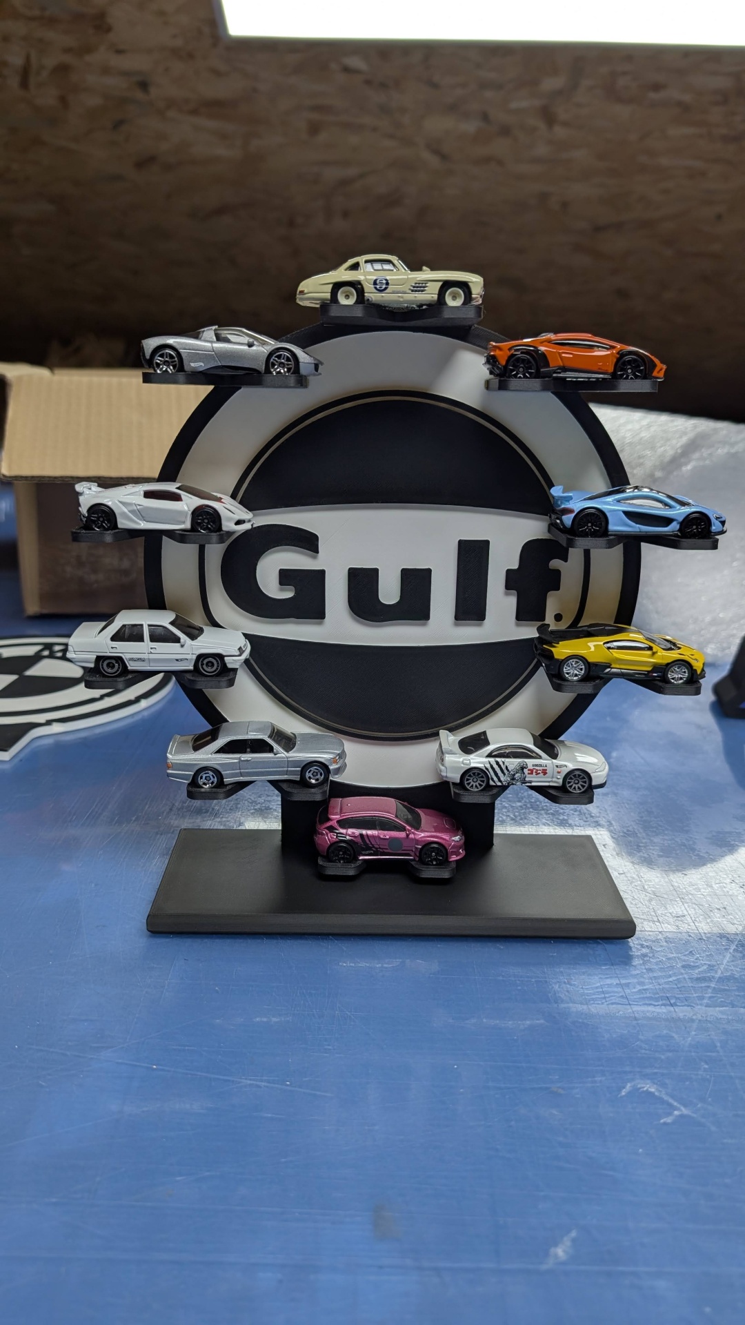 Mini carros coleccionáveis coloridos num suporte com logótipo Gulf