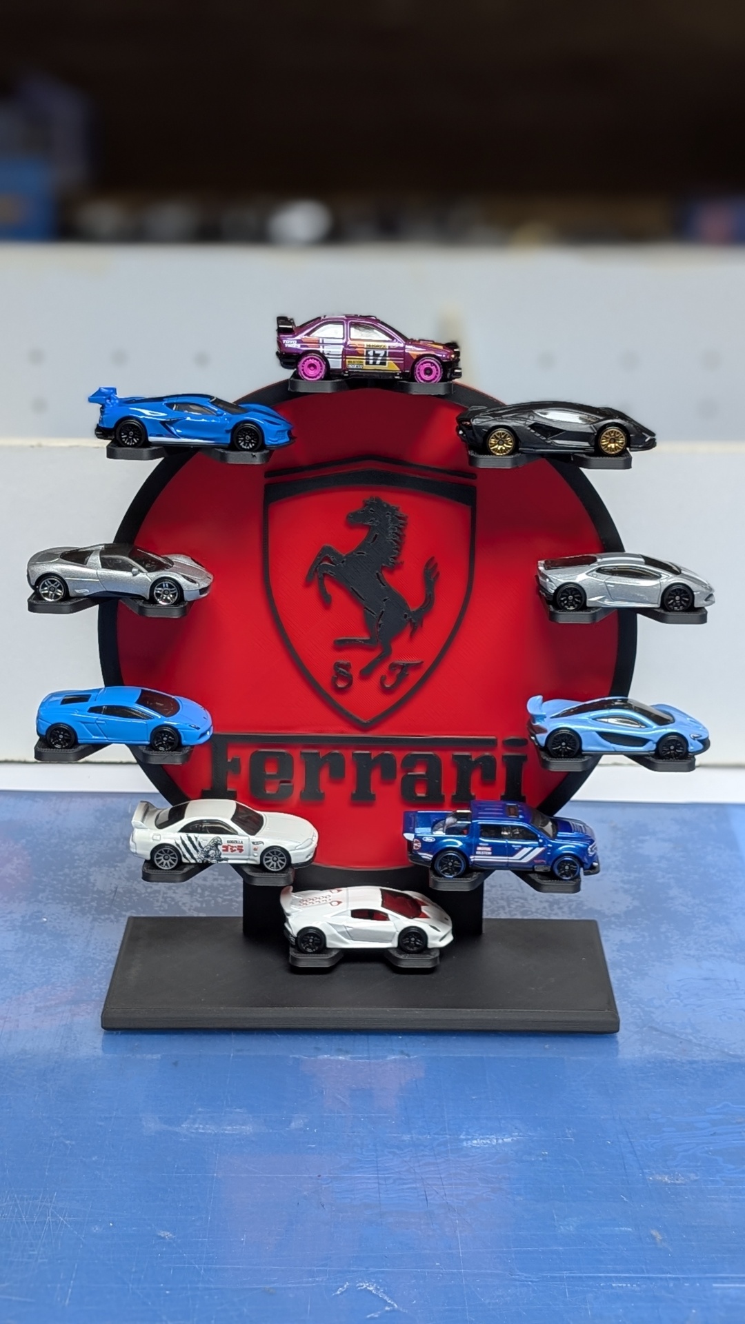 Conjunto de carros miniatura coloridos em suporte com logótipo Ferrari vermelho e preto