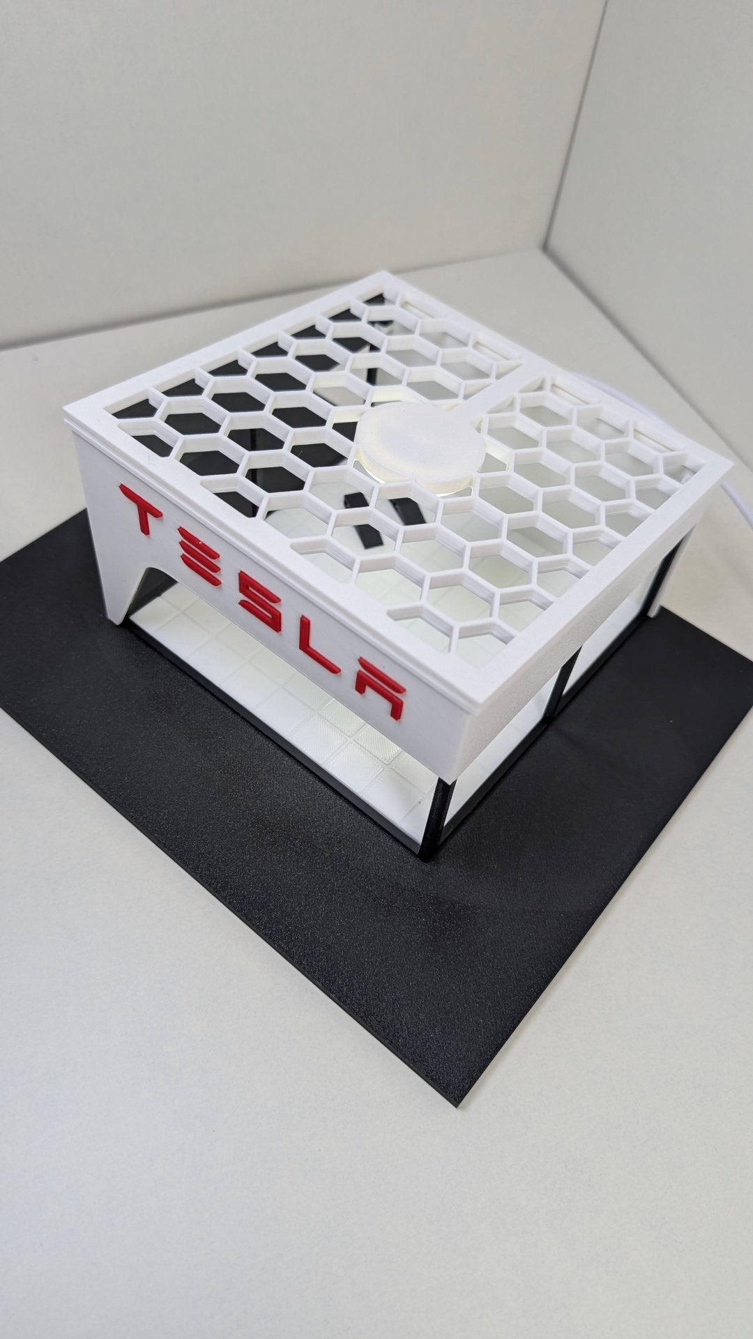 Modelo de edifício com letras TESLA em branco e vermelho sobre base preta