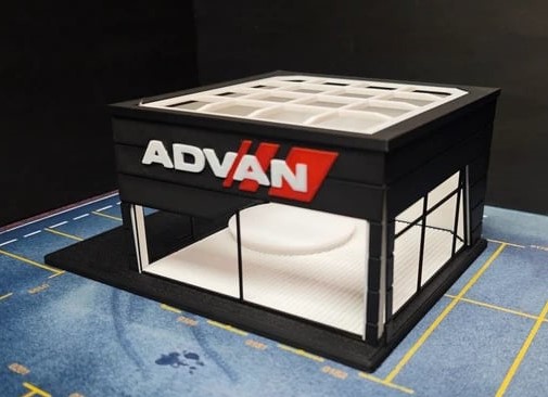 Modelo de exposição comercial quadrado preto com paredes de vidro e logotipo ADVAN em branco e vermelho na frente.