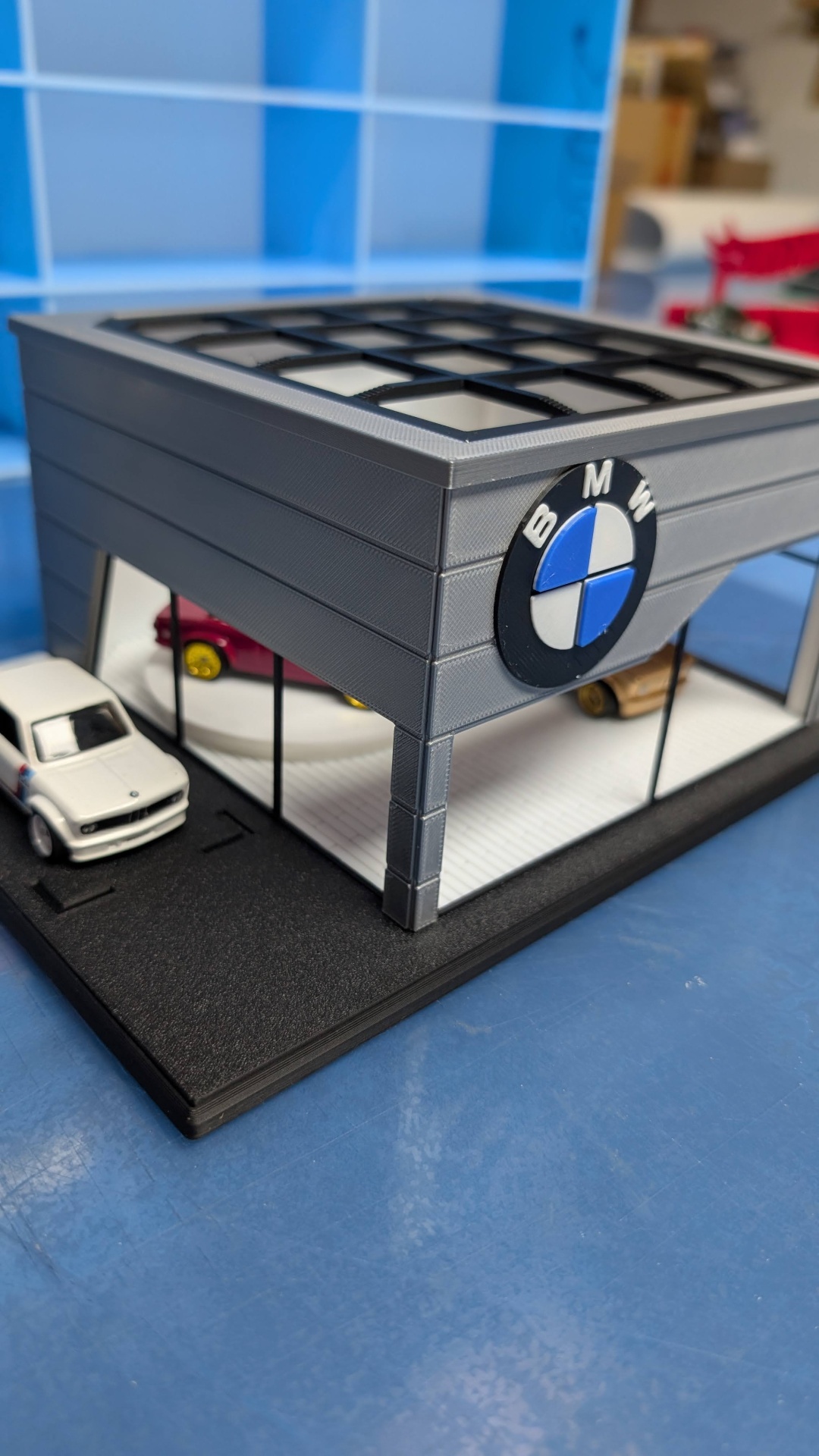Miniatura de concessionária BMW com carros miniatura e vidro transparente
