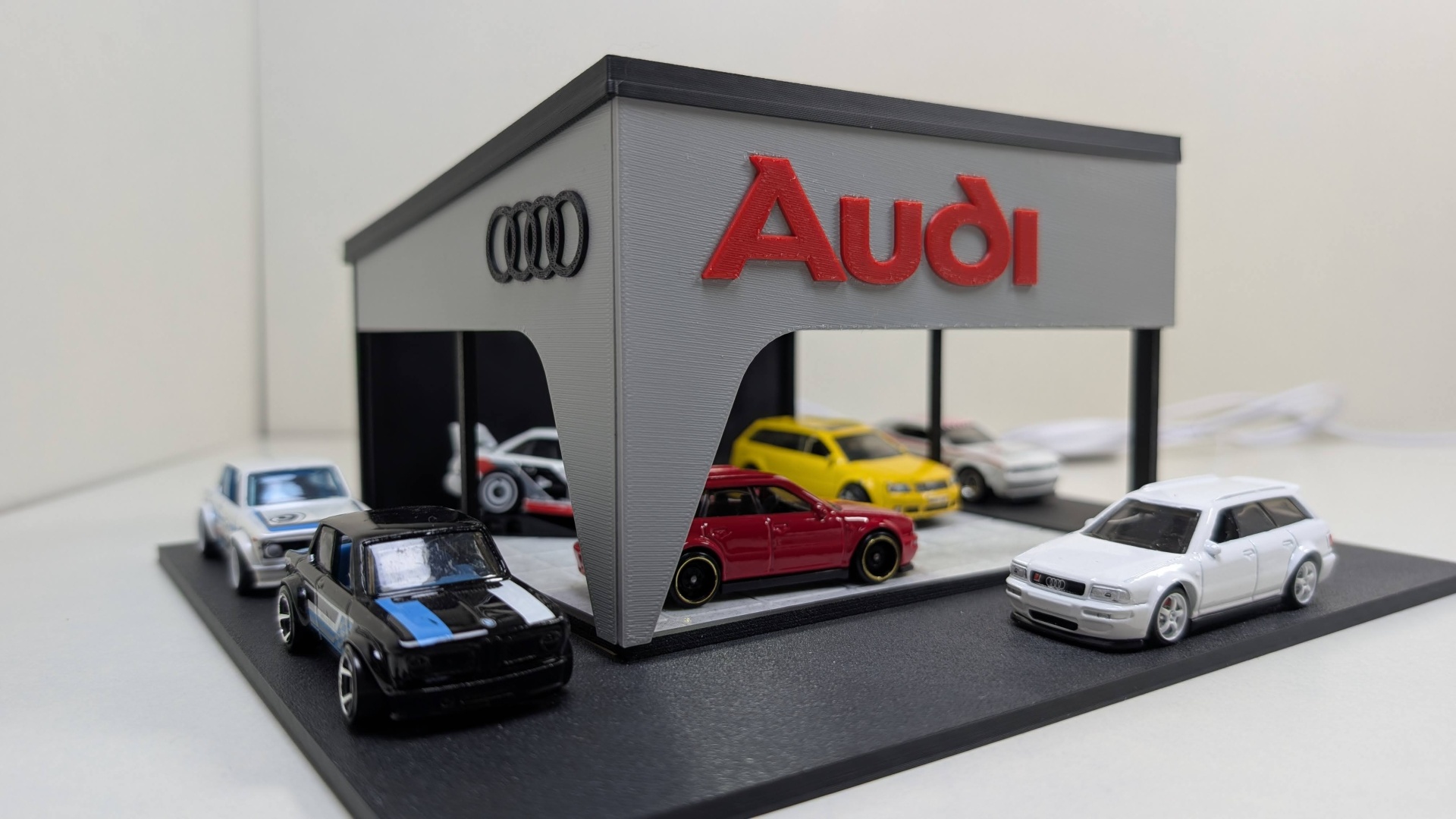 Miniatura de concessionária Audi com vários carrinhos em miniatura.