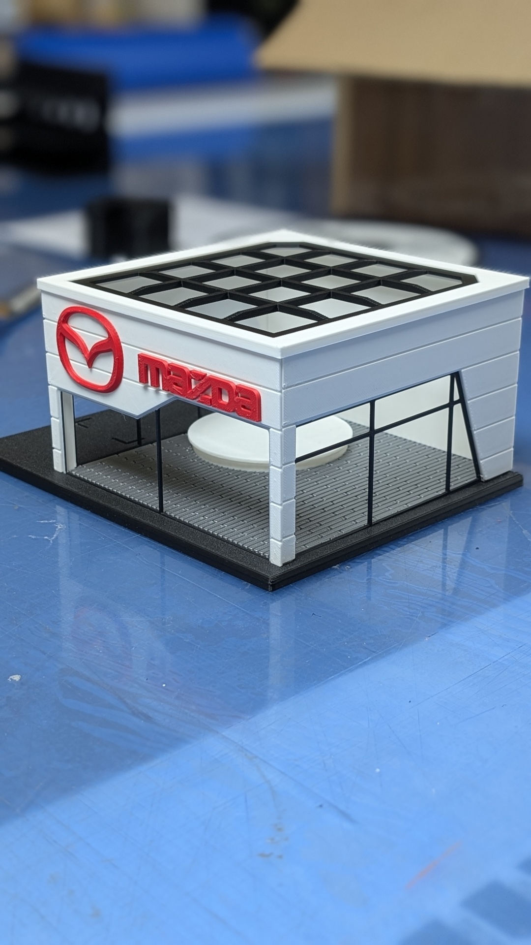 Miniatura de edifício branco com logo Mazda vermelho