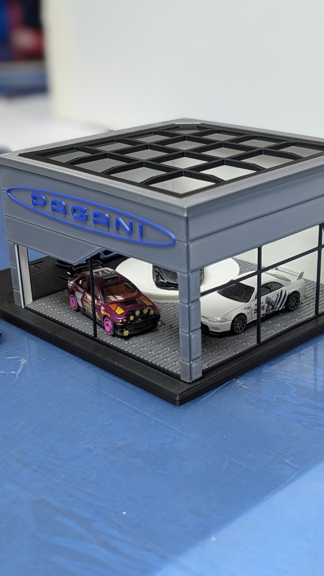 Miniatura de loja de carros com três miniaturas em seu interior