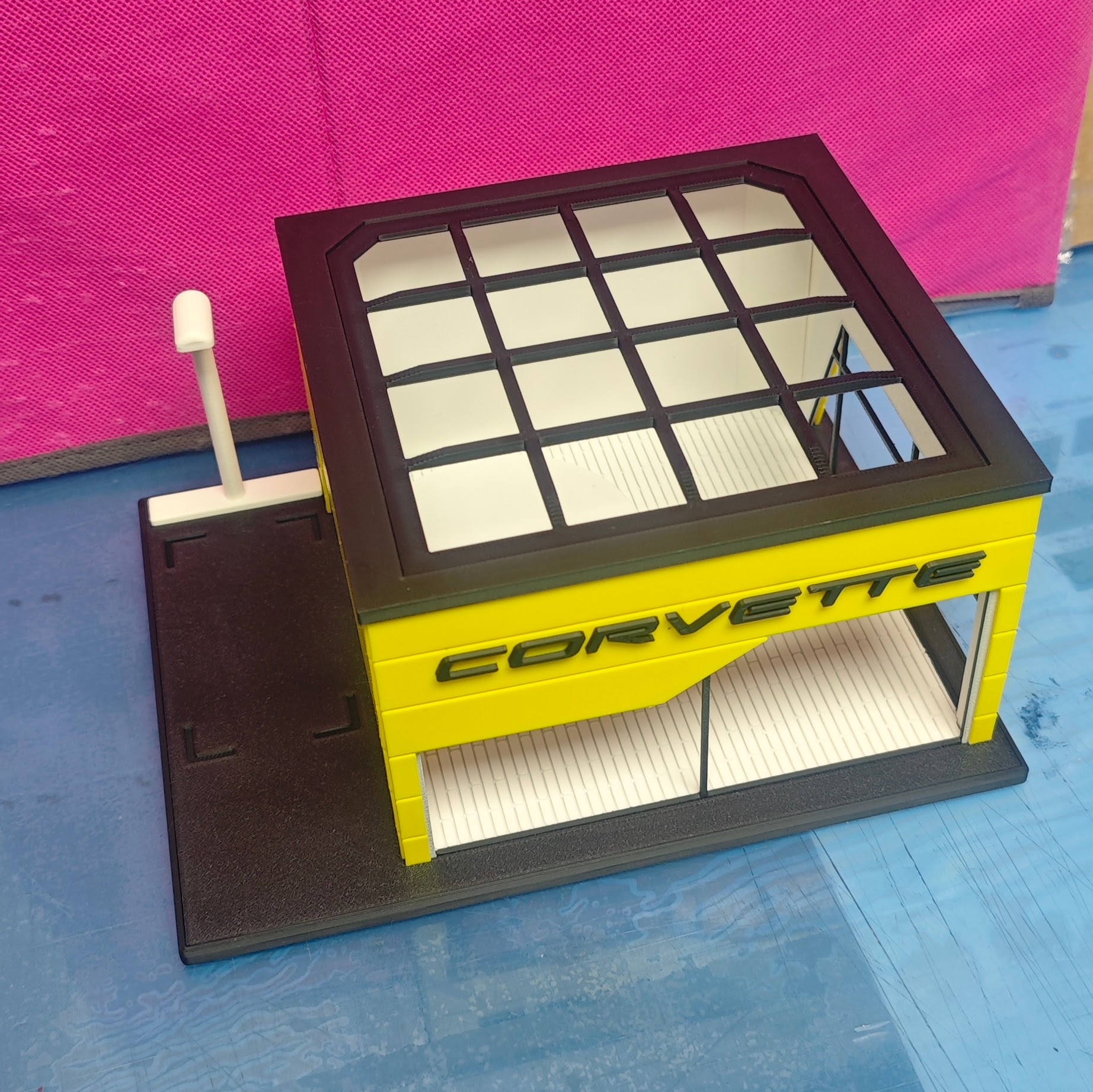 Miniatura de garagem amarela com teto preto e texto CORVETTE