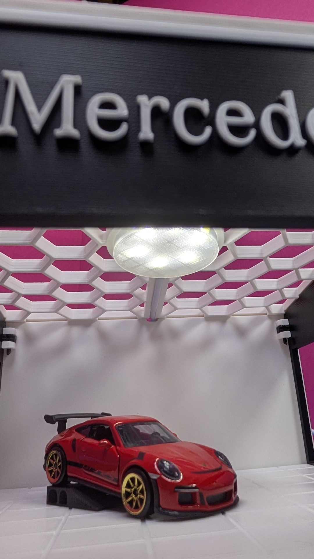 Carro de brinquedo desportivo vermelho com jantes douradas e asa traseira preta sob luz LED