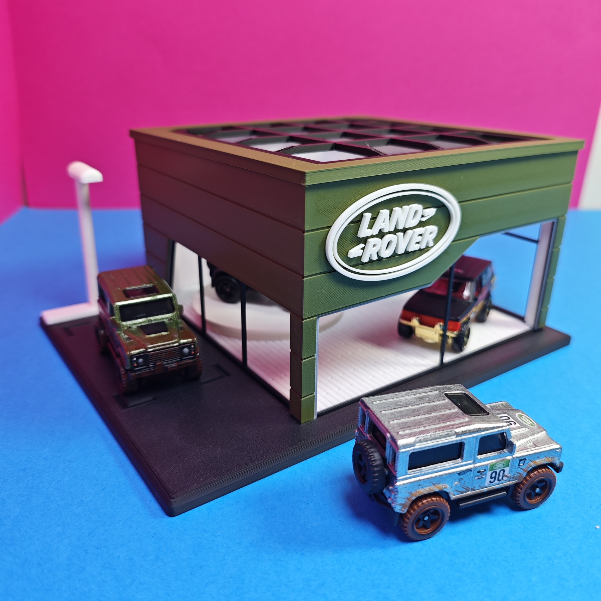 Modelo de loja Land Rover com três miniaturas de carros ao redor
