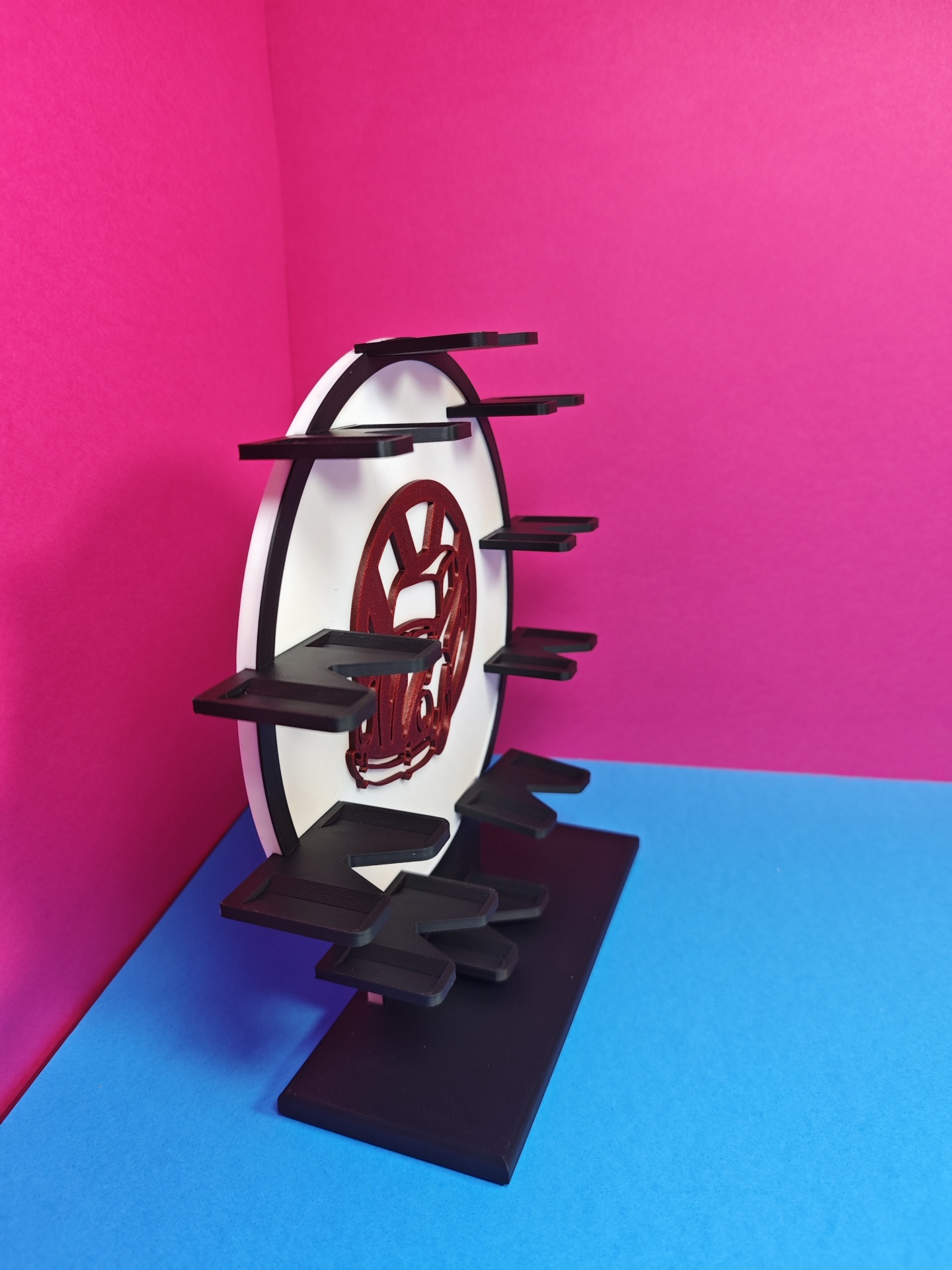 Suporte multi-nível plástico preto branco com recorte vermelho em fundo rosa azul