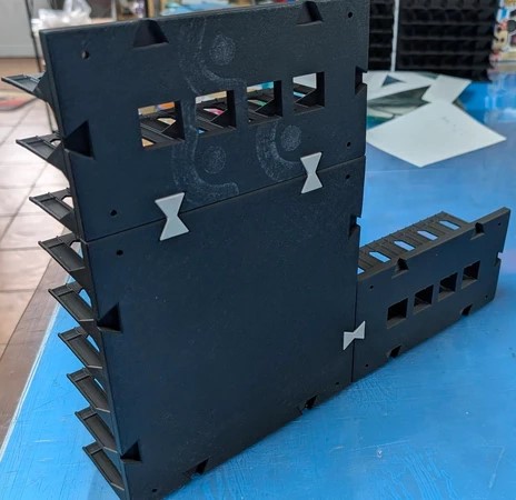 Estrutura modular preta com encaixes brancos sobre superfície azul