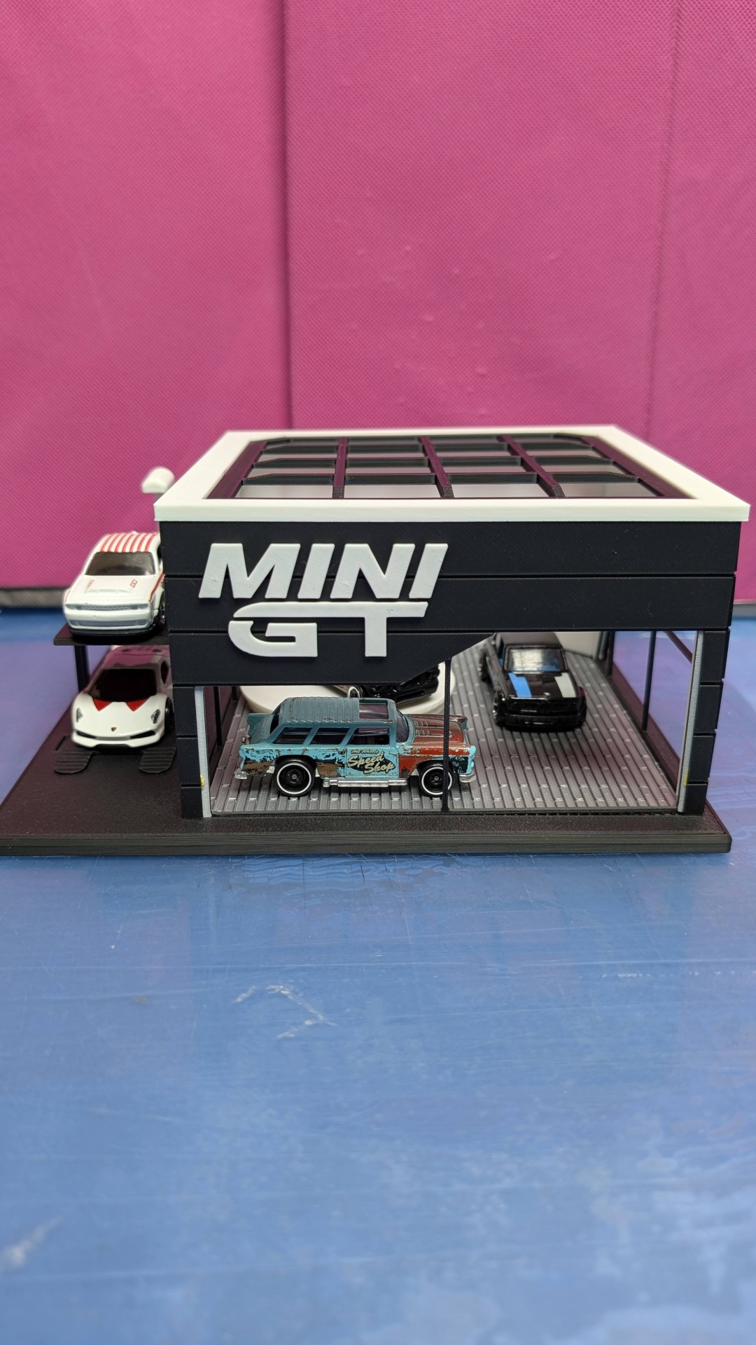 Miniatura de garagem com carros em miniatura e inscrição MINI GT