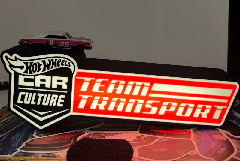 Miniatura de carro Hot Wheels cinzento e rosa com base preta e vermelho com texto