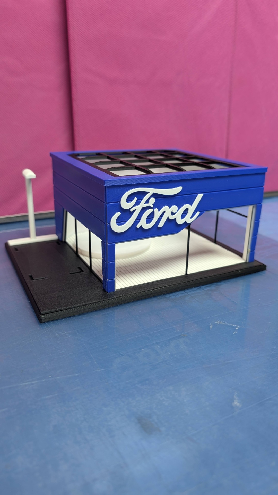 Modelo arquitetónico miniatura de loja Ford azul com texto branco e base preta