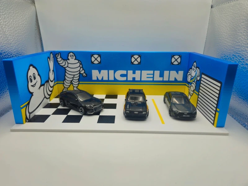 Miniatura de garagem com três carros e decoração Michelin