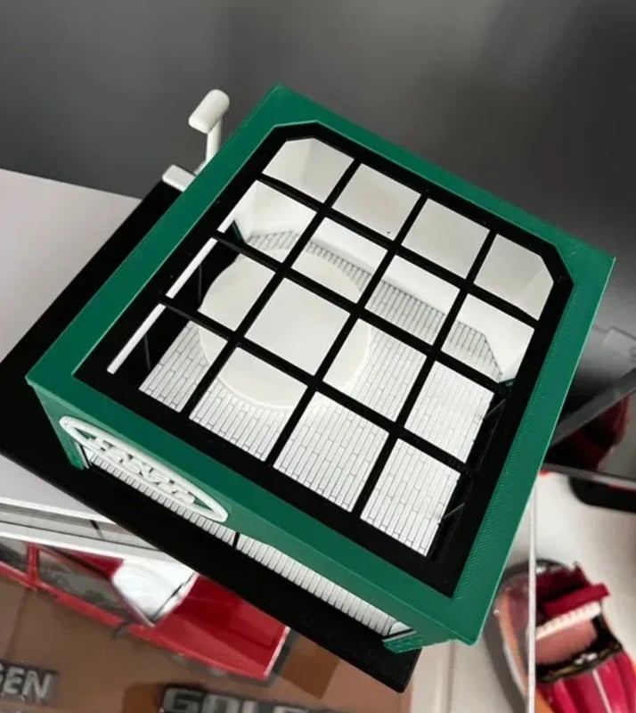 Miniatura de recinto verde com grelha preta e interior branco com padrão de tijolos