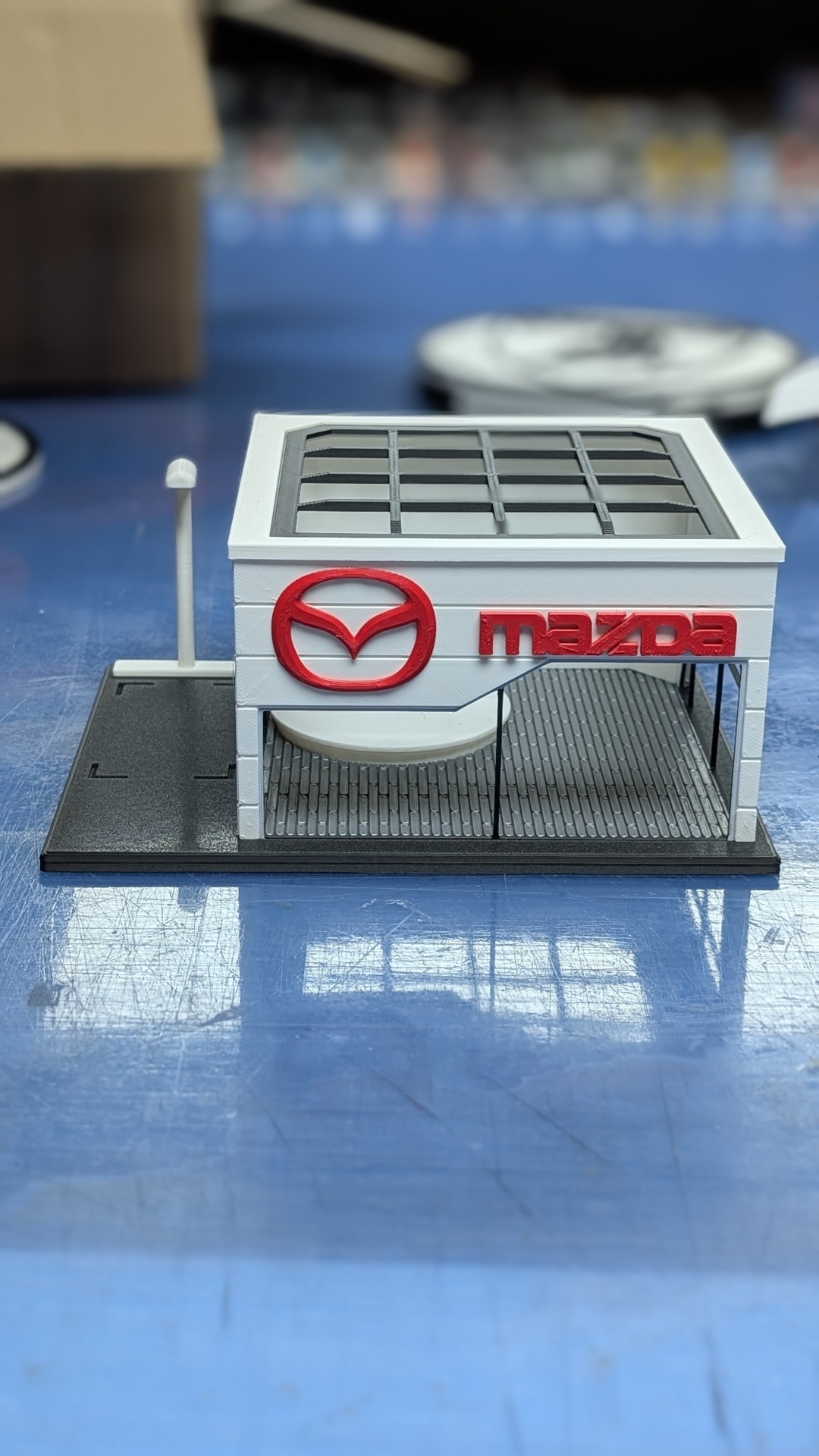 Miniatura de edifício com logo Mazda em relevo vermelho