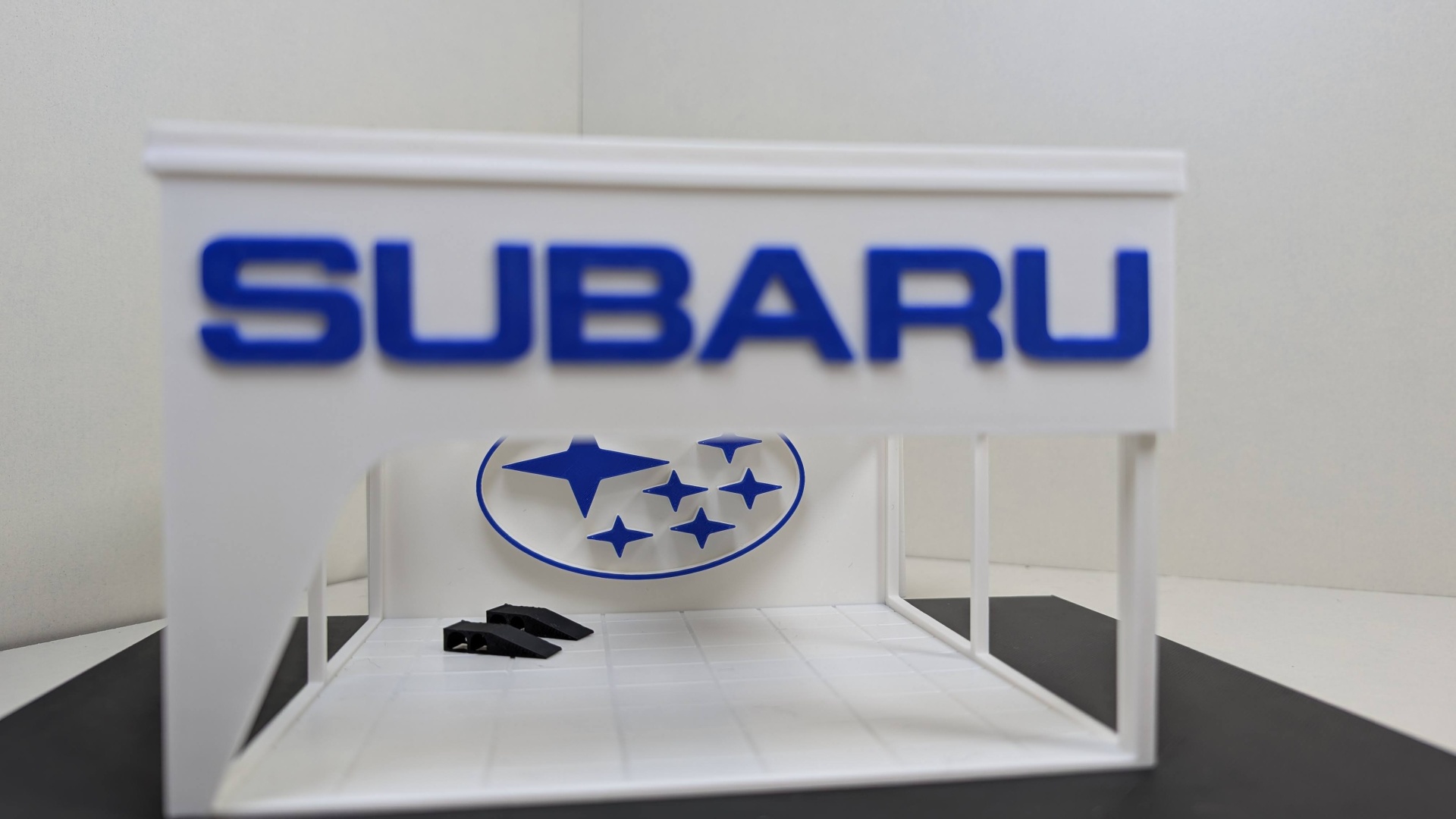 Miniatura estrutura branca com letras azuis SUBARU e logótipo de estrelas azuis
