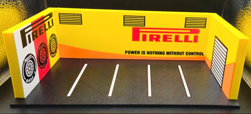 Miniatura de box de corridas Pirelli com paredes amarelas, chão preto e logos Pirelli