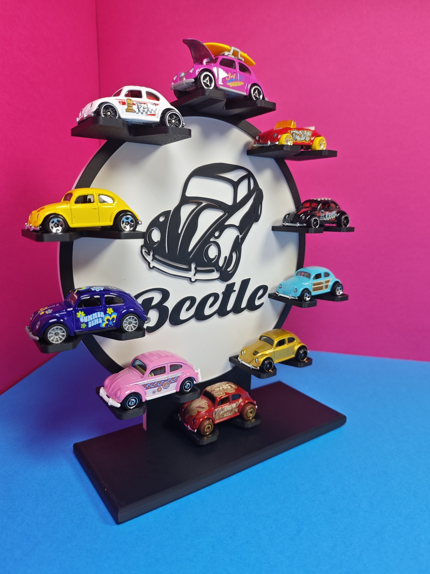 Expositor de miniaturas de carros Beetle coloridos sobre base preta com fundo rosa.