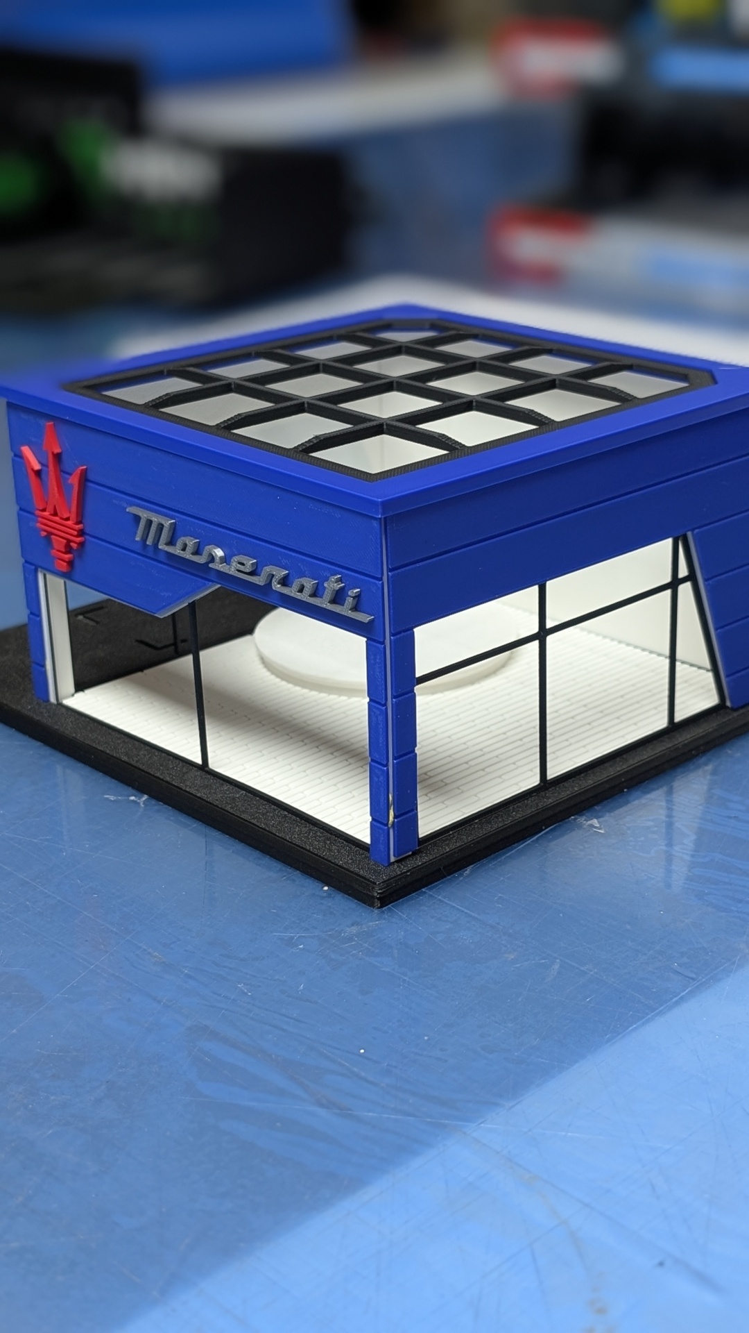 Maquete de loja Maserati azul com janelas e logo vermelho e prateado