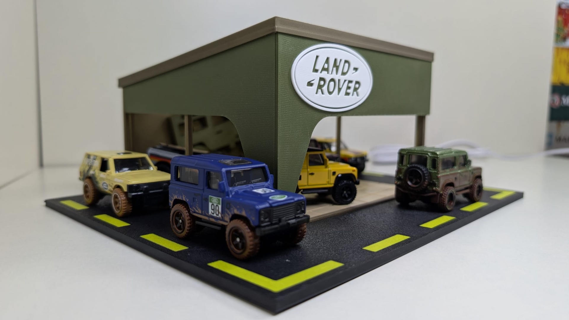 Diorama com carros Land Rover miniatura em exposição com tecto verde e logótipo
