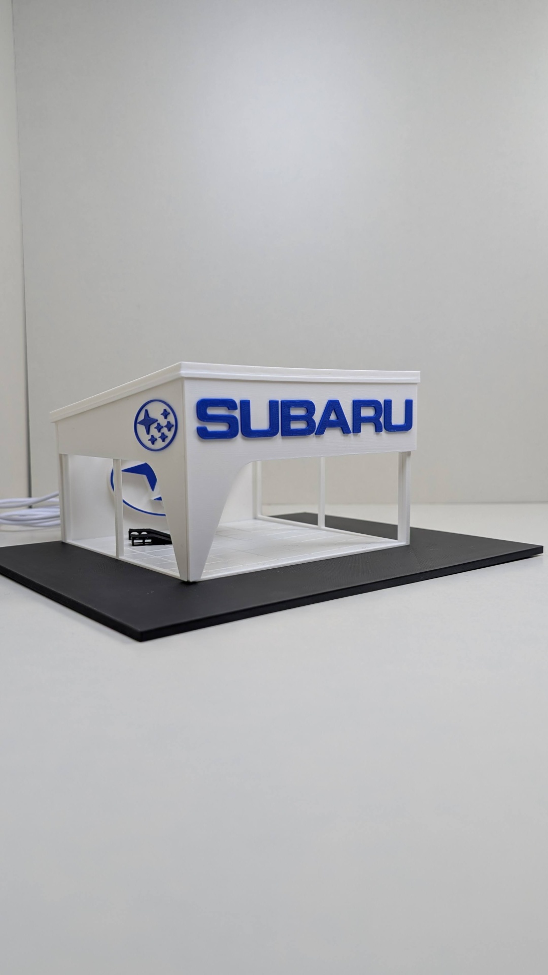 Modelo em miniatura de loja Subaru em branco e azul com base preta